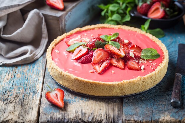 Tarta con fresas y crema de mascarpone batida decorada con fresas frescas sobre madera rústica