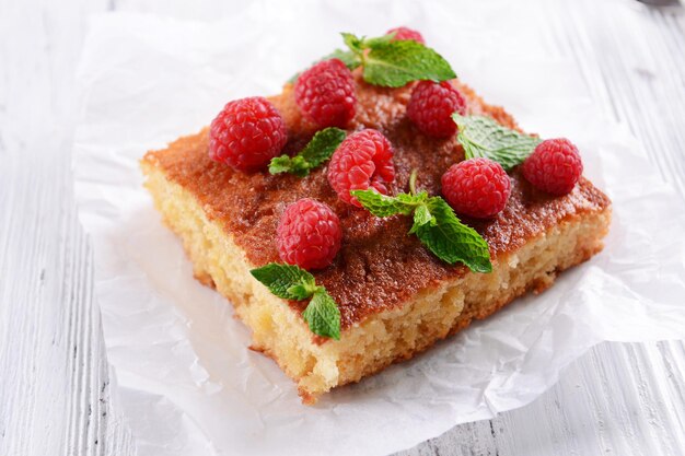 Tarta fresca con frambuesa en pergamino en primer plano de la mesa de madera