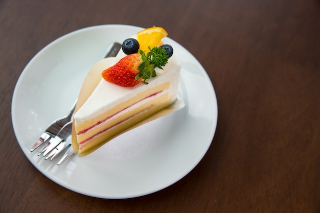 Tarta de frutas con crema batida fresa y arándanos y naranja en la mesa de madera