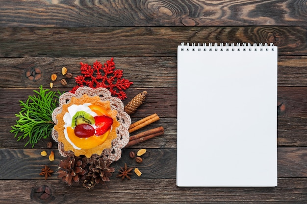 Foto tarta de frutas de navidad y decoraciones copo de nieve, servilleta de ganchillo, piñas. copyspace