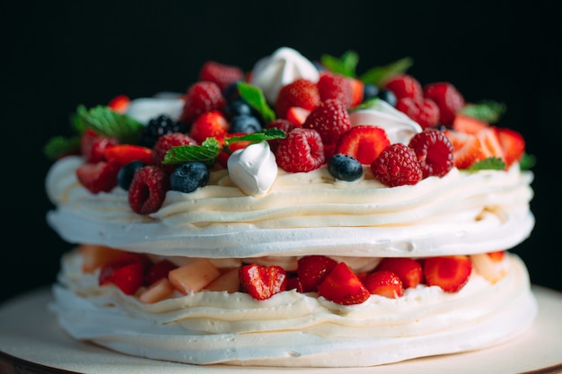 Tarta de frutas. Pastel decorado con bayas en soporte de madera en negro