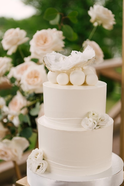 Tarta grande blanca decorada con flores y plumas para el bebé