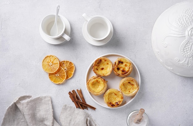 Tarta de huevo típica portuguesa pastel de nata con tazas de café en la vista superior de fondo de hormigón