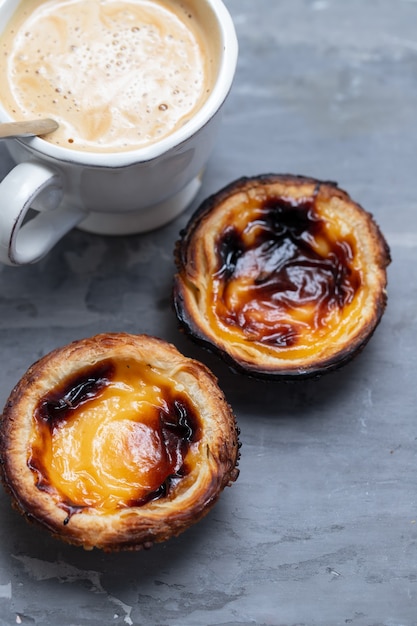 Tarta de huevo típico portugués pastel de nata con taza de café sobre fondo de cerámica