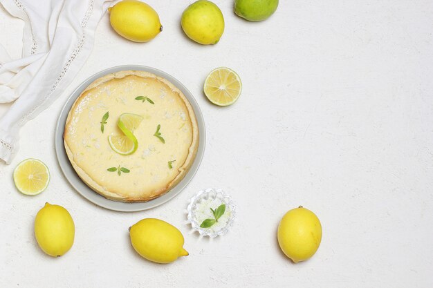 Tarta de lima sobre madera blanca con limas