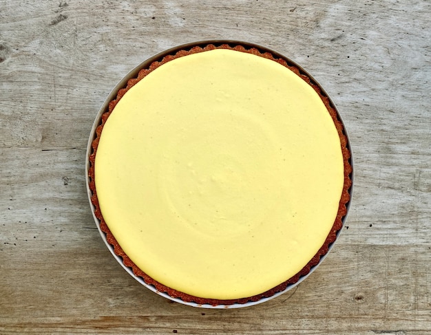 Foto tarta de limón entero fresco en la mesa de la cocina de madera, vista superior