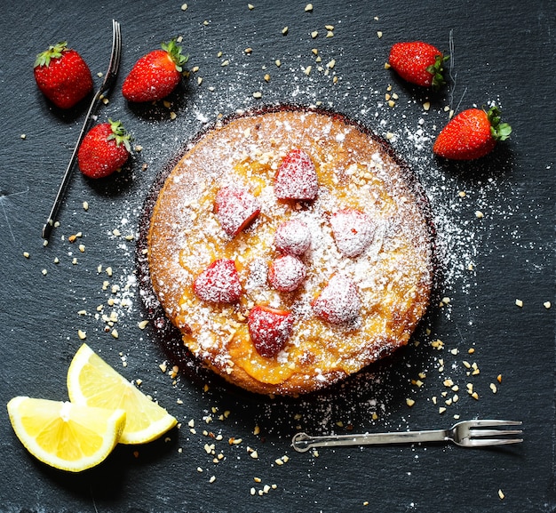 Foto tarta de limón con fresas, azúcar y chocolate