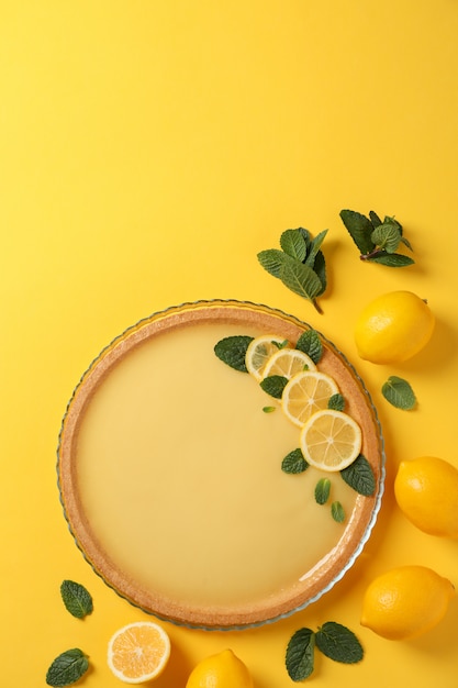 Tarta de limón, menta y limones sobre fondo amarillo, vista superior