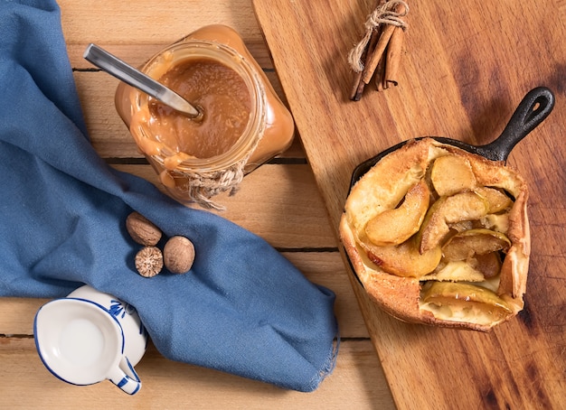 Tarta de manzana casera con salsa de caramelo en una mesa de madera. Vista superior. Cerca de una jarra de caramelo, leche y especias. Sabroso postre