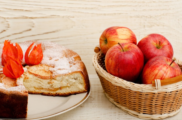 Tarta de manzana, flores Physalis y manzanas maduras en una mesa de madera clara, primer plano