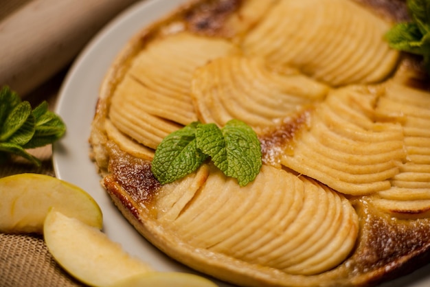 Tarta de manzana francesa sobre su base de hojaldre crujiente son rodajas de manzanas jugosas mezcladas con nuez moscada de azúcar moreno y otras especias Decorado con hojas de menta