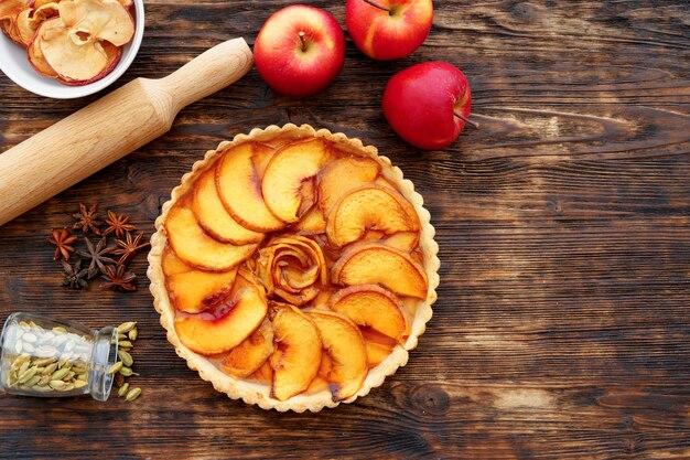 Tarta de manzana y manzanas rojas en la mesa de madera de cerca