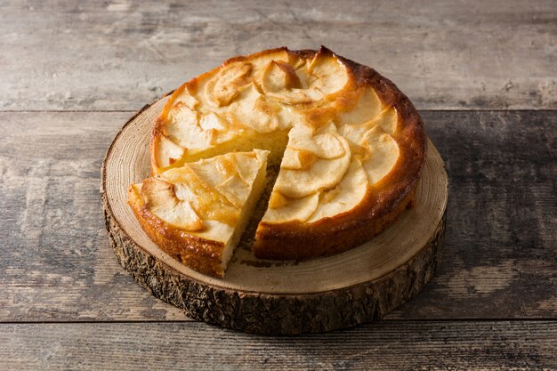 Tarta de manzana rebanada casera en mesa de madera.