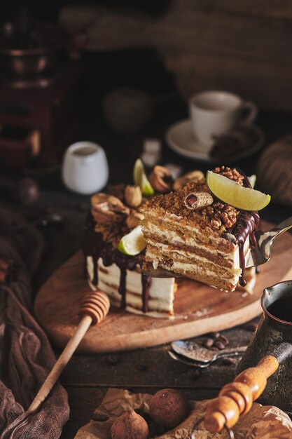 Tarta de miel casera clásica. Un pastel de cumpleaños con miel, chocolate, nueces y mantequilla de nueces. Postre en una tabla de madera.