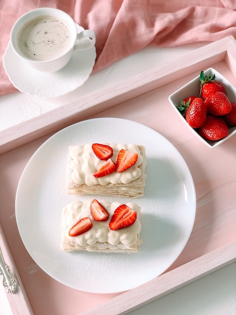 Tarta milfey con crema y fresas y taza de café