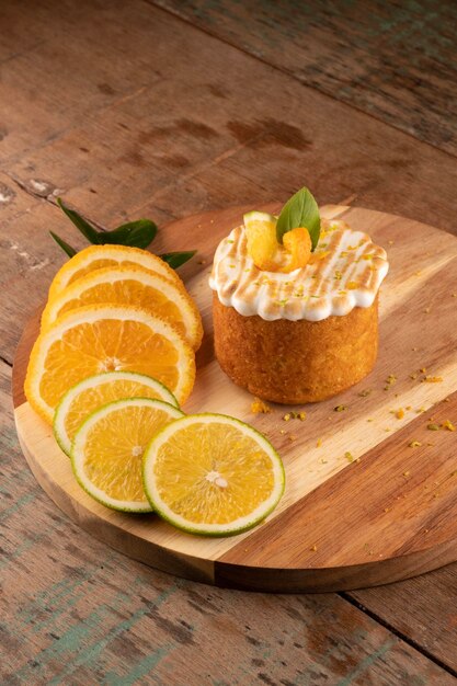 Tarta de naranja con cobertura de crema blanca tostada sobre una mesa rústica de madera en bistró con vista angular de rodajas de naranja