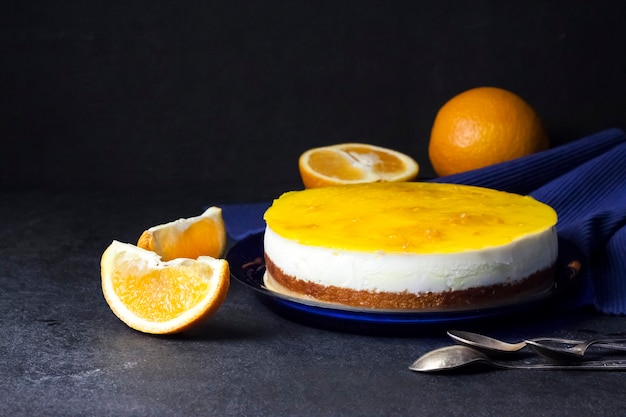 Tarta de naranja con mousse de crema y gelatina de naranja sobre fondo oscuro
