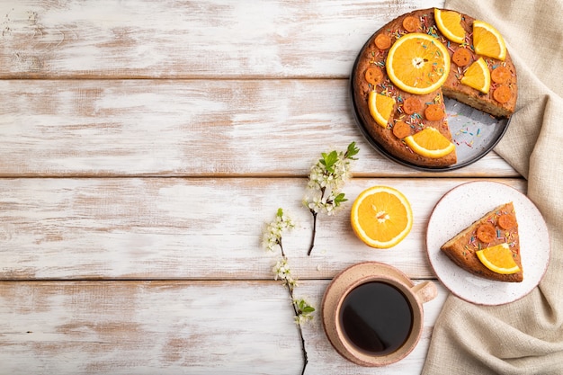 Tarta de naranja y una taza de café en una madera blanca