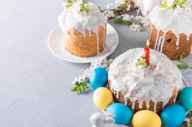 La tarta de Pascua y los huevos pintados de amarillo en la mesa gris decorados con flores de primavera