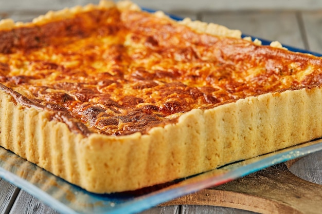 Tarta con patatas y queso en placa de vidrio sobre fondo de madera