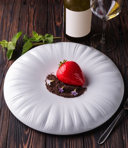 Tarta de postre de fresa roja con chispas de chocolate y violetas en un plato blanco grande.