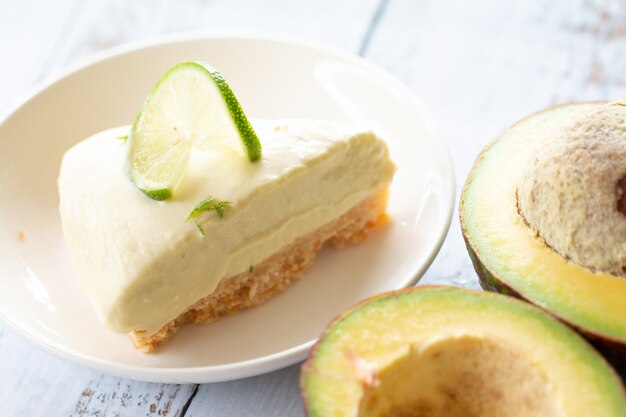 Tarta de queso de aguacate y lima hecha en casa sobre una madera blanca