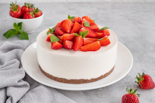 Sin tarta de queso al horno con fresas frescas y menta en la parte superior de un plato blanco Copiar espacio