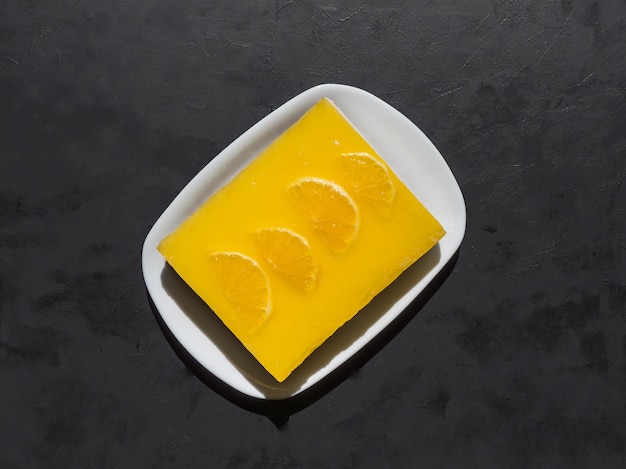 Tarta de queso amarillo con naranjas sobre fondo negro