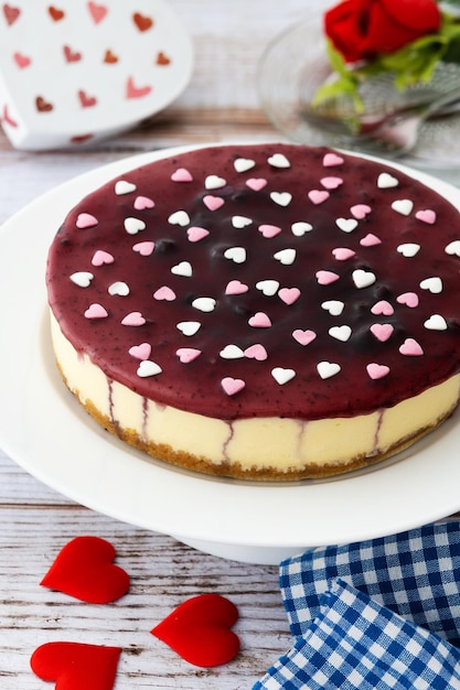 Tarta de queso con arándanos decorada con corazones dulces en una mesa de madera