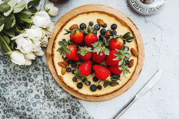 Tarta de queso con arándanos fresa almendra sobre el fondo de hormigón blanco con servilleta