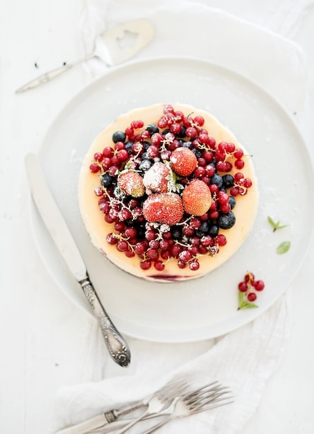 Tarta de queso con bayas frescas del jardín en la parte superior sobre la superficie de la mesa de madera blanca Enfoque selectivo