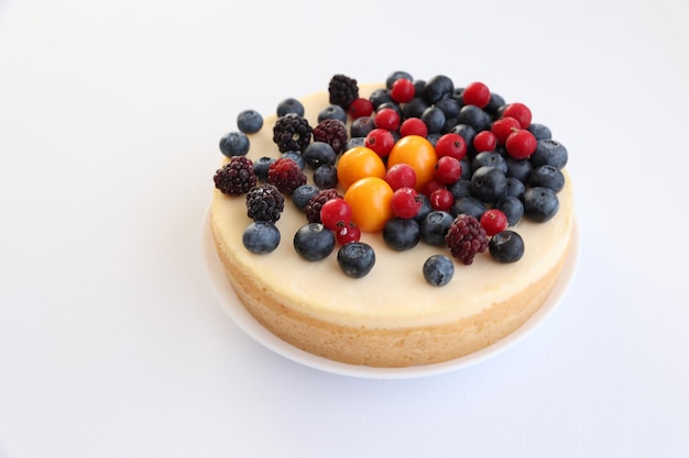 Tarta de queso con bayas sobre un fondo blanco.