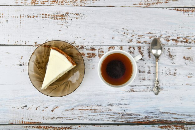 Tarta de queso con café en una luz de madera. Café en una cafetería, copia. Tarta de queso de Nueva York en un hormigón ligero, vista desde arriba. Tarta de queso clásica y una taza de café.