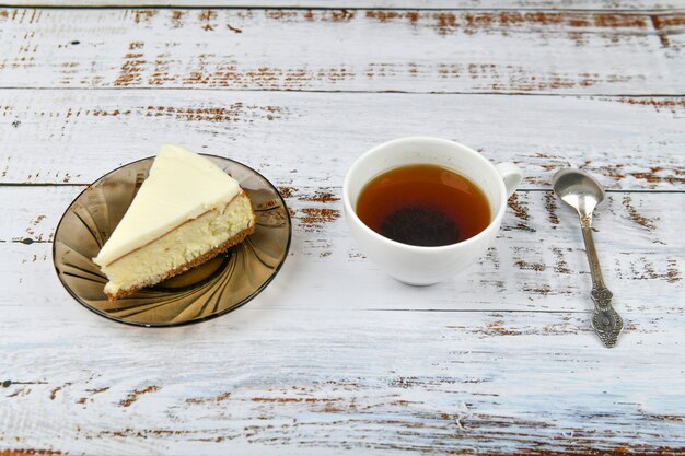 Tarta de queso con café en una luz de madera. Café en una cafetería, copia. Tarta de queso de Nueva York en un hormigón ligero, vista desde arriba. Tarta de queso clásica y una taza de café.