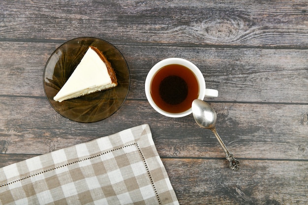 Tarta de queso con café en una madera oscura. . Un pastel de queso junto a él en un marrón de madera. Copa retro. Café en una cafetería, copia.