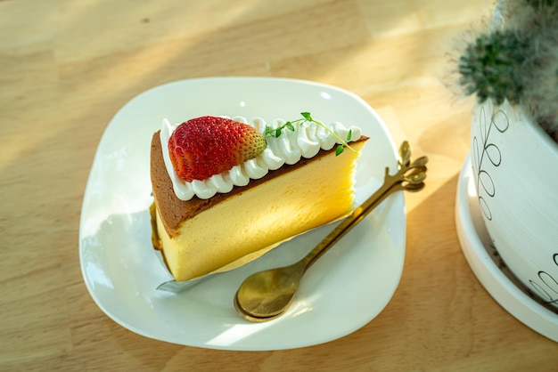 Tarta de queso casera con fresas en un plato en un escritorio de oficina de escritorio de madera en una cafetería en el jardín durante el trabajo de negocios