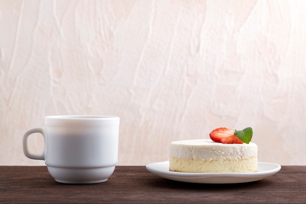 Tarta de queso clásica de Nueva York con fresas y una taza de café o té.