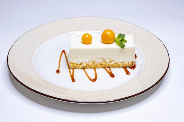 Tarta de queso clásica de nueva york con physalis y jarabe en un plato blanco y un fondo delicioso