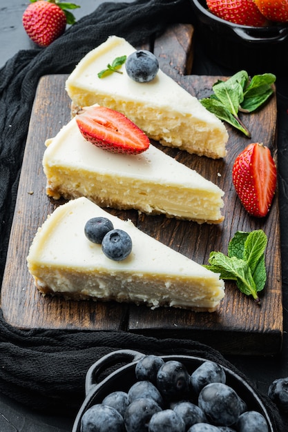 Tarta de queso clásica de Nueva York, en rodajas, sobre mesa negra