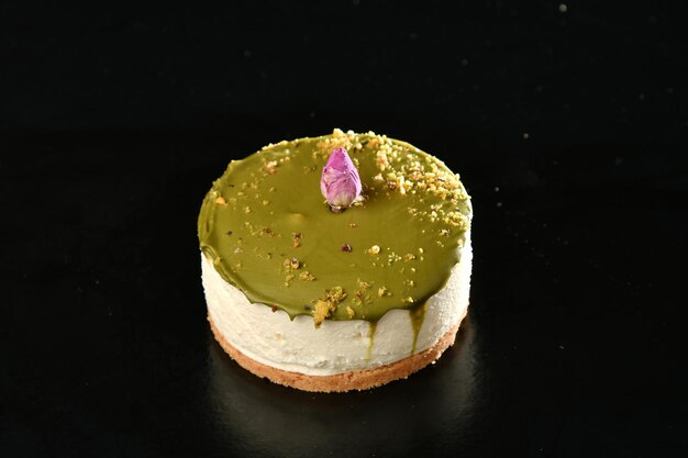 Una tarta de queso con cobertura verde y una flor encima.