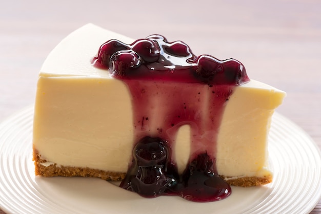 Tarta de queso crema de arándanos en plato blanco sobre mesa de madera