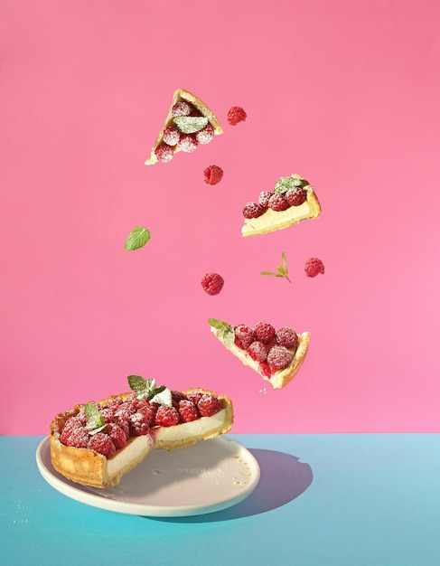 Tarta de queso con frambuesa fresca y piezas voladoras sobre fondo azul y rosa espacio de copia libre