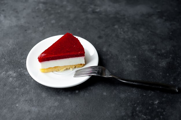 Tarta de queso con frambuesas en un plato blanco sobre un fondo de piedra