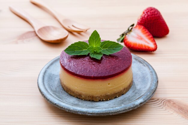 Tarta de queso de fresa con menta fresca sobre fondo de madera.