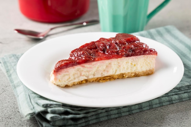 Tarta de queso glaseada con fresa en vajilla blanca sobre la mesa