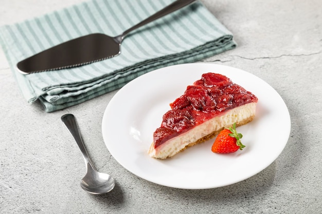 Foto tarta de queso glaseada con fresa en vajilla blanca sobre la mesa