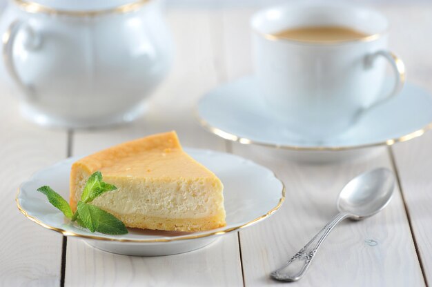 Foto tarta de queso y una hoja de menta en el plato con un borde dorado