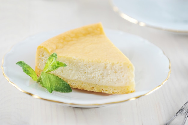 Tarta de queso y una hoja de menta en el plato con un borde dorado