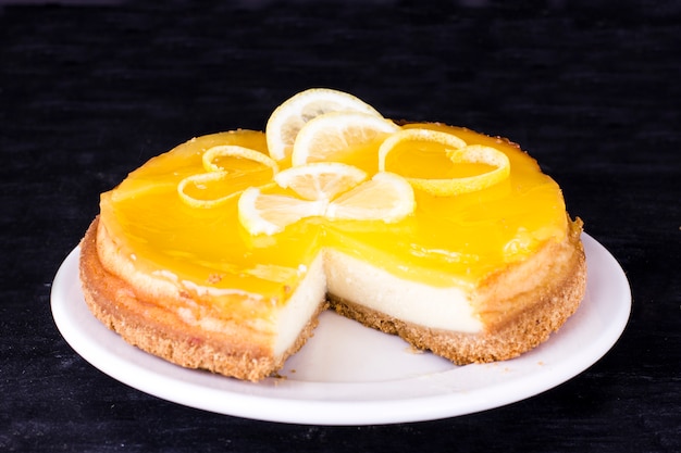 Tarta de queso de limón sobre fondo negro decorado con ralladura de limón de cerca