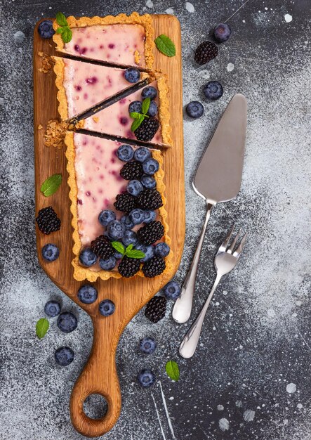 Tarta de queso con moras frescas, arándanos y menta sobre un fondo de piedra gris